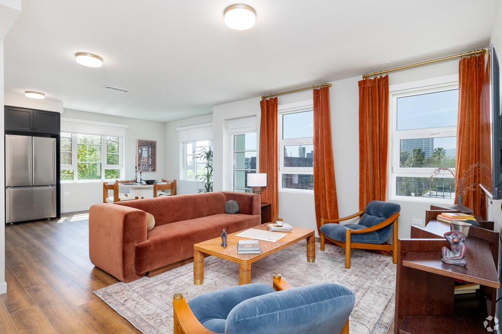 a living room with orange curtains and a brown couch