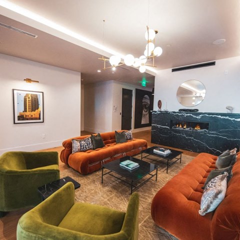 a living room with orange couches and green chairs and a fireplace
