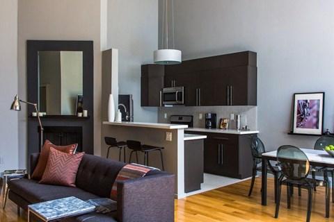 A modern living room with a black couch and a fireplace.