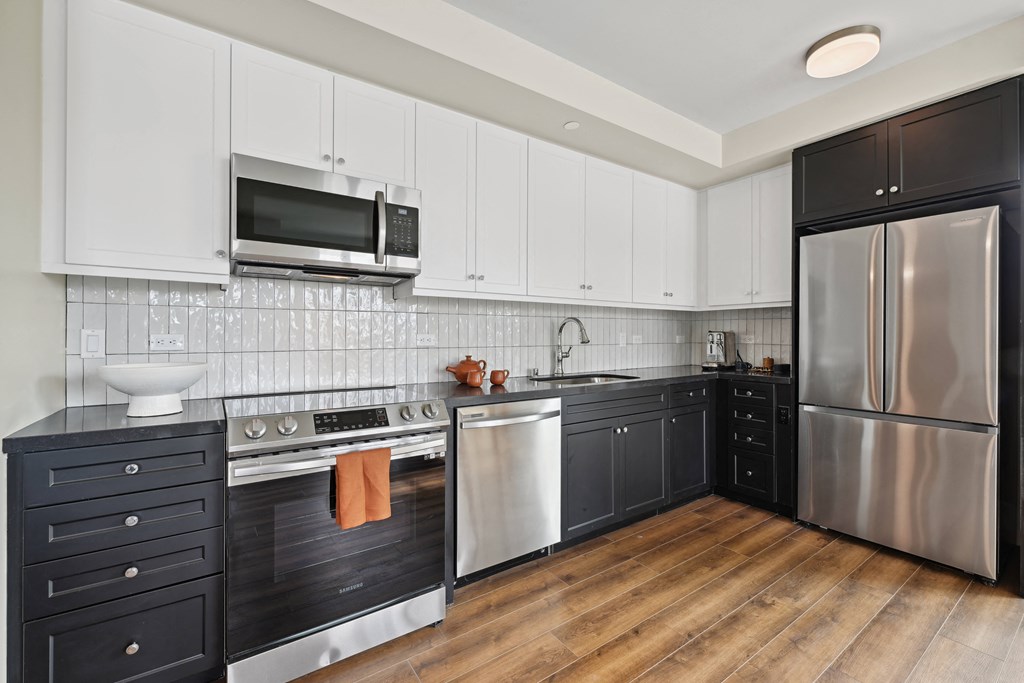 a kitchen with black and white cabinets and stainless steel appliances