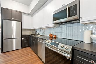 a kitchen with white cabinets and stainless steel appliances at The Baxter Apartments, Los Angeles, CA