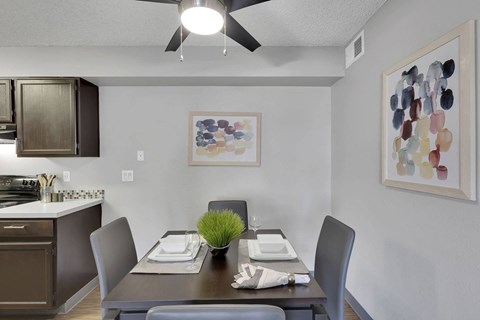 A dining room with a table set for two and a ceiling fan.
