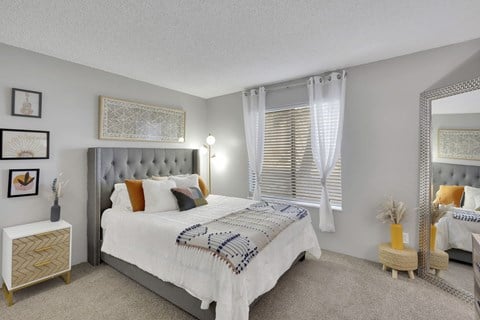 A bedroom with a large bed and a mirror on the wall.
