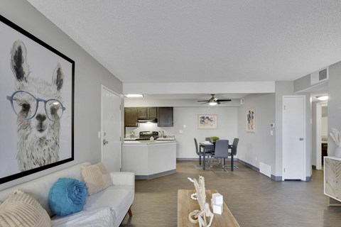 A living room with a white couch and a painting of a llama wearing glasses.