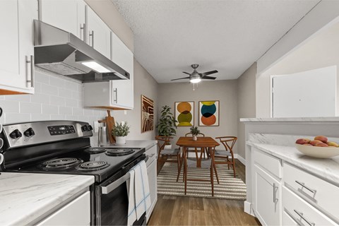 A kitchen with a stove top oven and a table with chairs.
