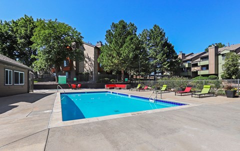 A swimming pool surrounded by lounge chairs and trees.