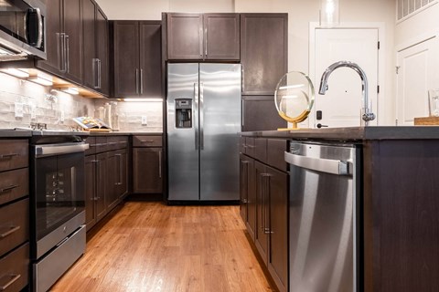 A modern kitchen with dark wood cabinets and stainless steel appliances.