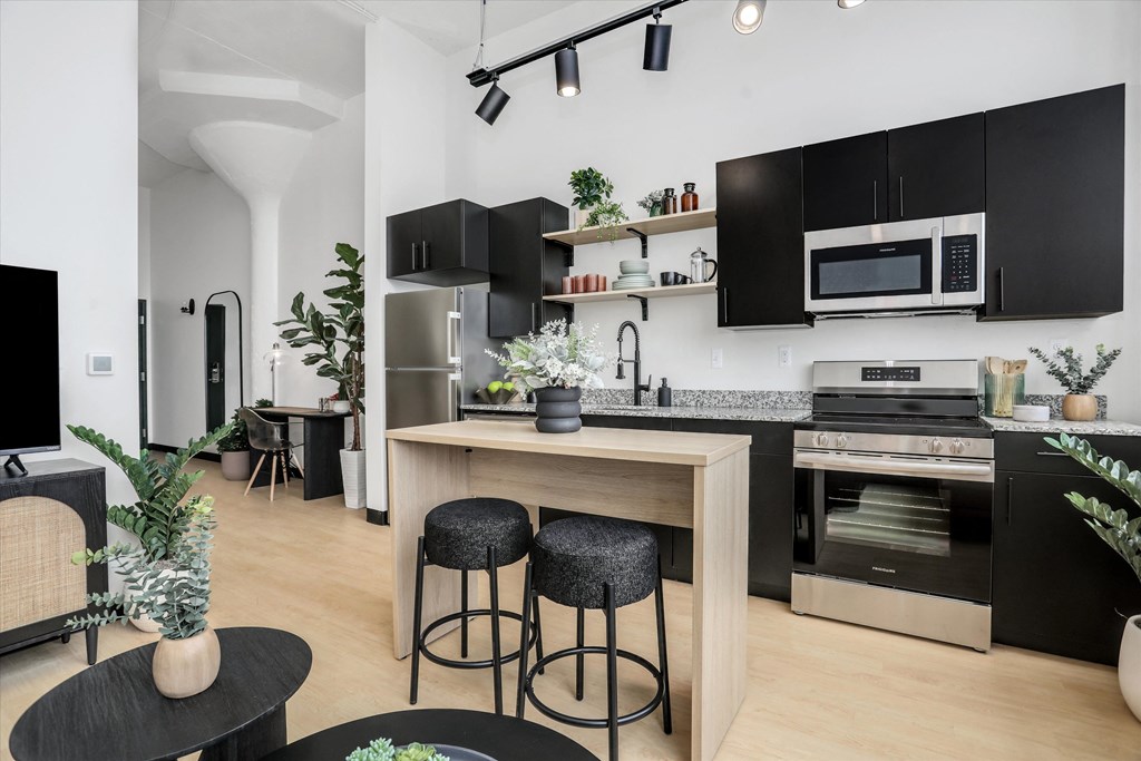 a kitchen with black cabinets and a counter with two stools