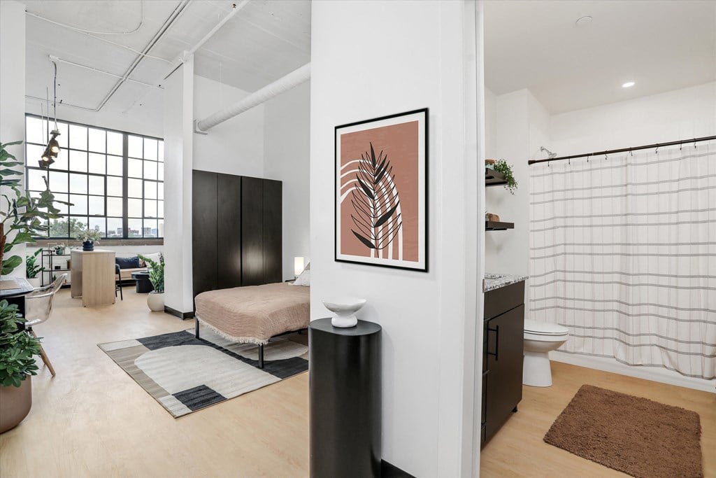 a living room with a bed and a bathroom with a shower