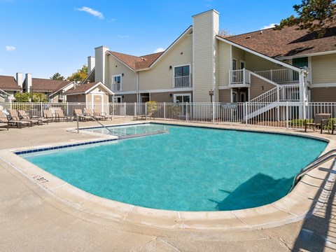 A swimming pool in front of a building with a white fence around it.