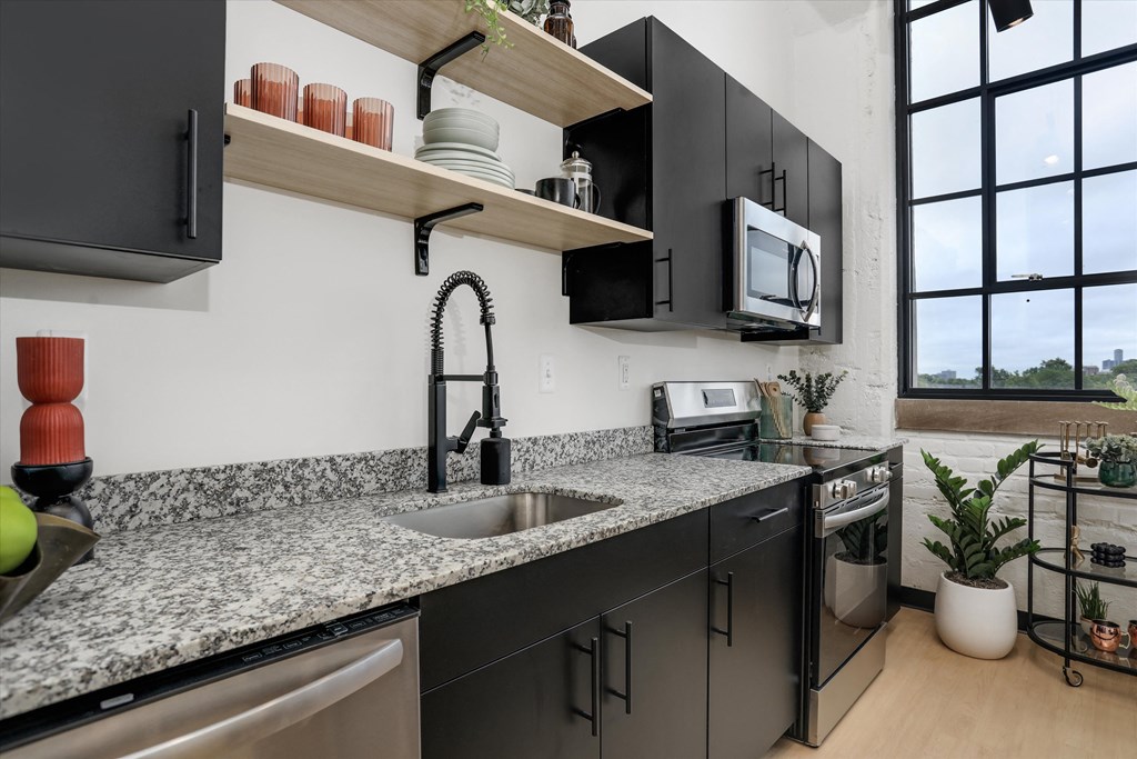 a kitchen with granite counter tops and black cabinets and a sink