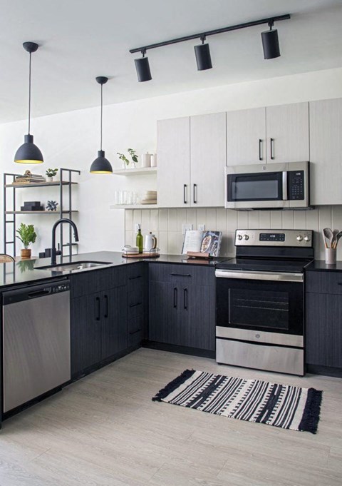 a kitchen with black and white cabinets and stainless steel appliances