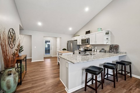 A kitchen with white cabinets and a marble countertop.