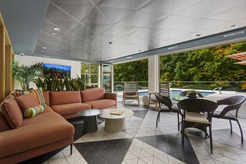 A living room with a television and a pool outside.