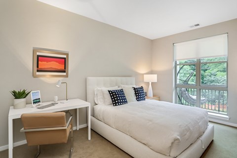 a bedroom with a bed and a desk and a window