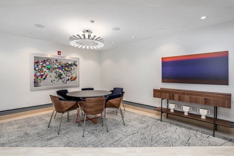 a dining room with a table and chairs and a painting on the wall