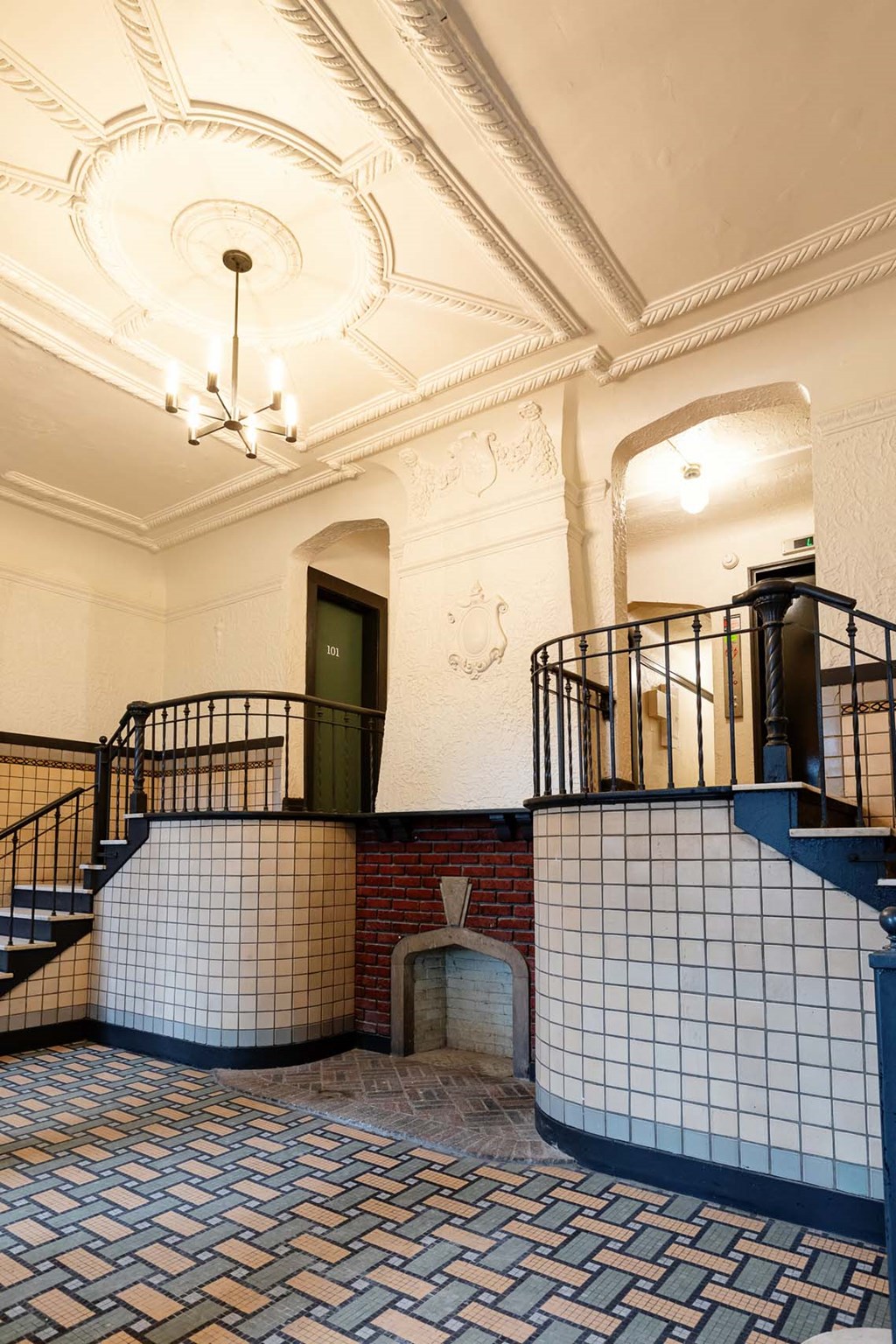 the lobby of a building with stairs and a blue and white tiled floor