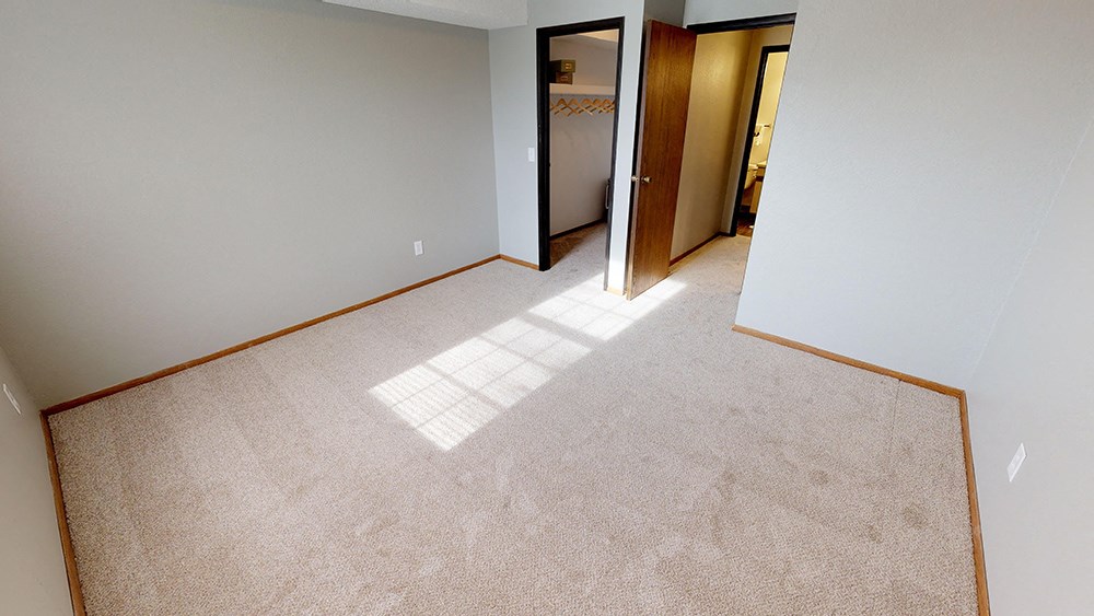 A room with a carpeted floor and a window.