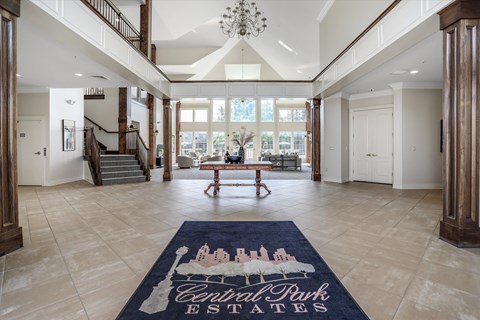 A large open living room with a blue carpet that says Central Park Estates.