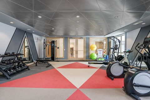 a gym with exercise equipment and windows on a red and white floor