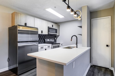 A modern kitchen with a stainless steel refrigerator and a white countertop.