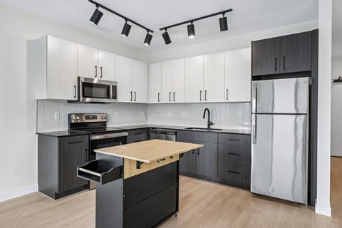 A modern kitchen with a wooden island and stainless steel appliances.