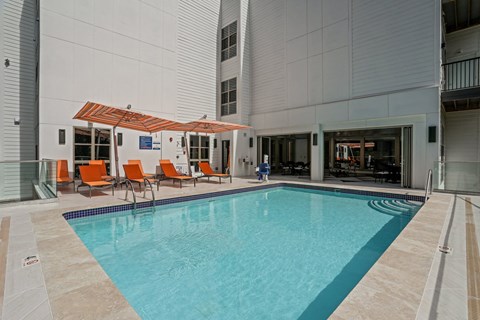 the pool area of a building with a pool and orange chairs