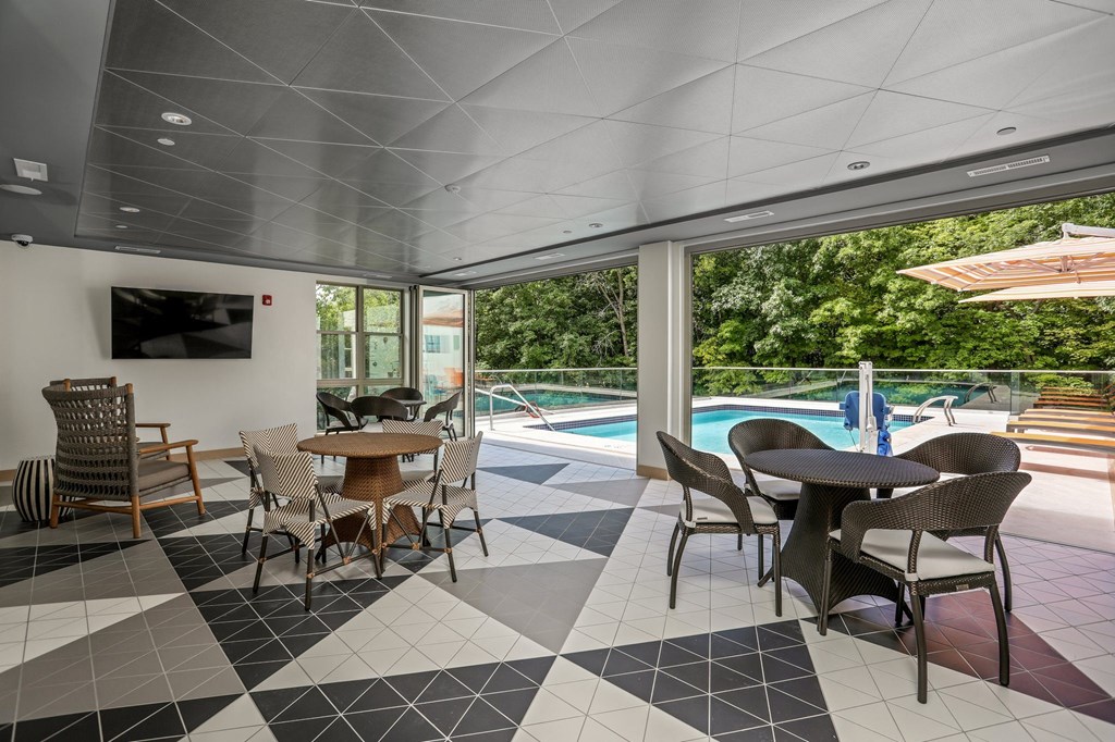 a lounge area with tables and chairs and a pool in the background