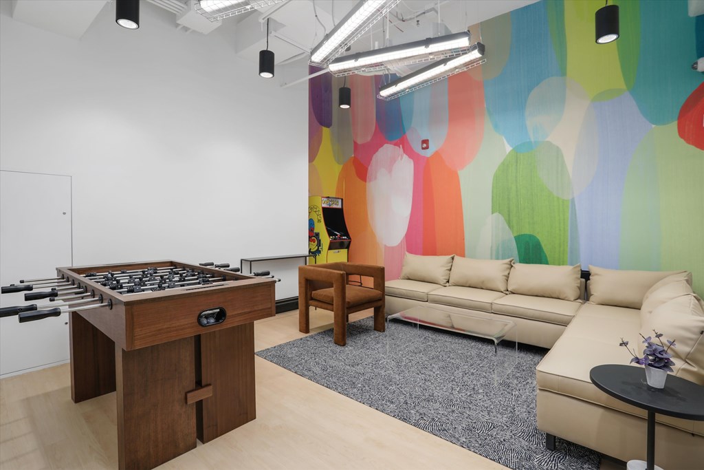 A room with a foosball table and a couch.