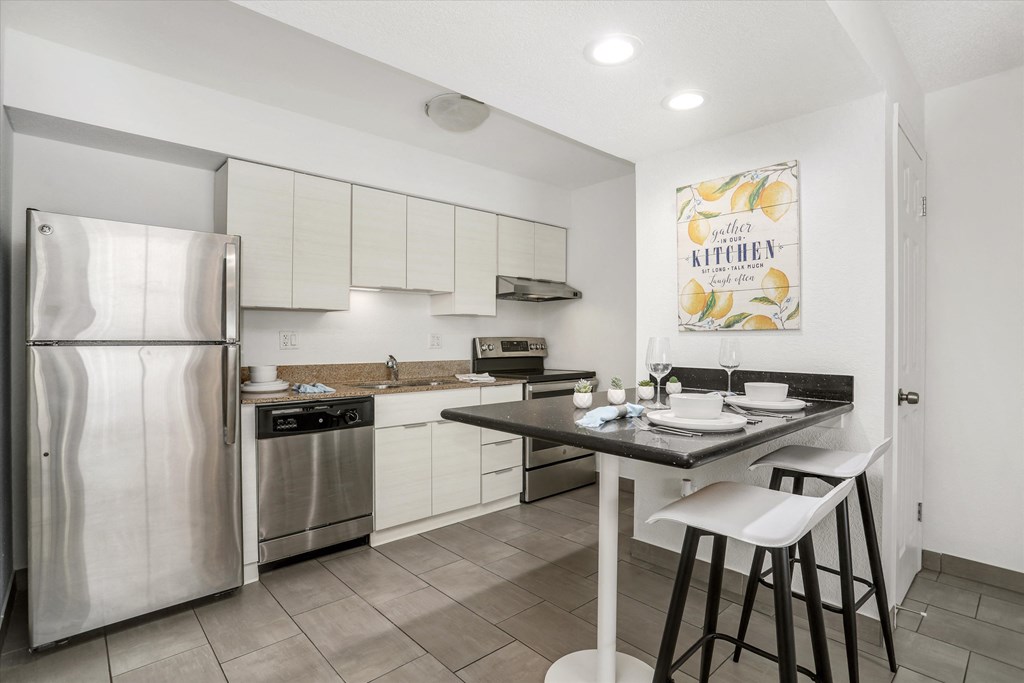 a kitchen with stainless steel appliances and a bar with two stools