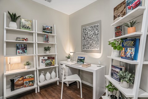 a home office with a white desk and shelves