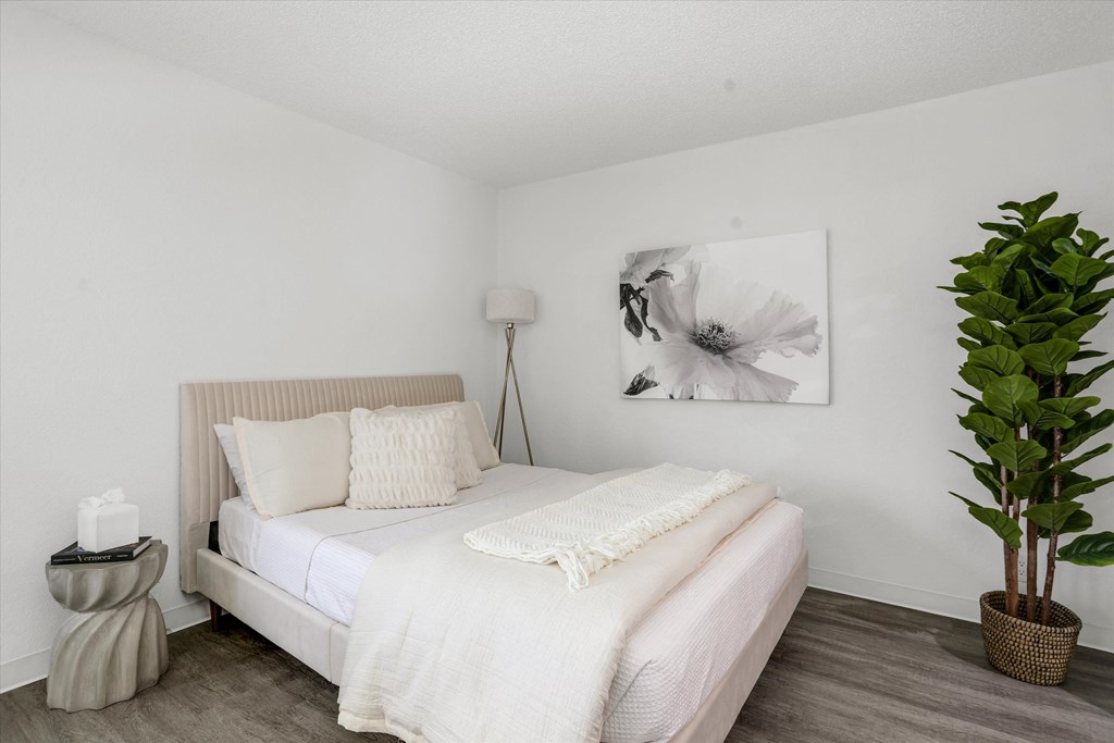a bedroom with a white bed and a large potted plant