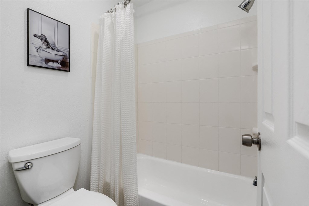 a bathroom with a tub and a toilet and a shower curtain