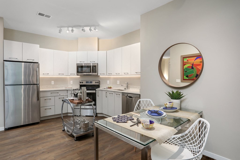 a kitchen with white cabinets and stainless steel appliances and a dining table