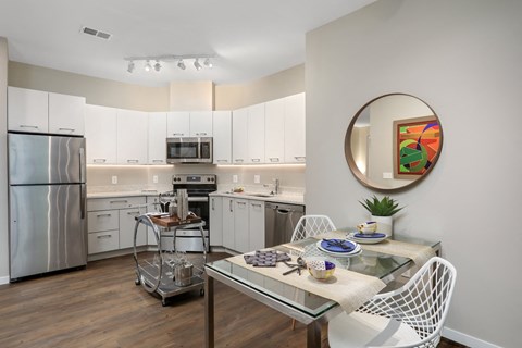 a kitchen with white cabinets and stainless steel appliances and a dining table