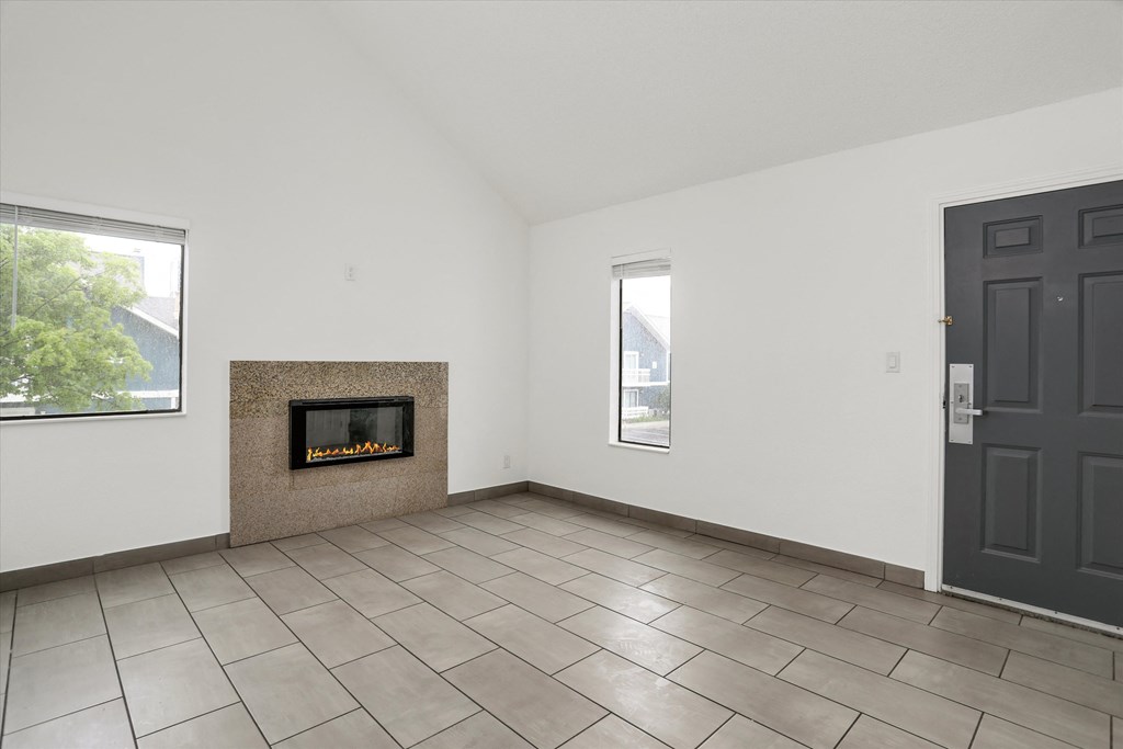 an empty living room with a fireplace and a black door