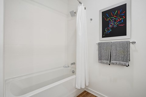 A white bathroom with a white tub and a picture on the wall.