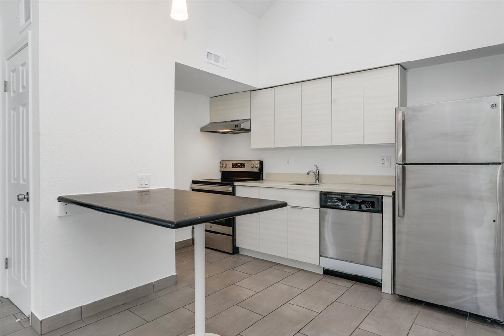 an empty kitchen with stainless steel appliances and a black counter top