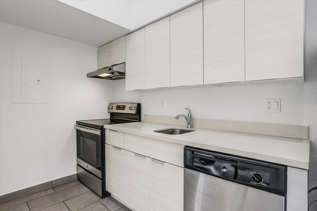 an empty kitchen with a sink and a dishwasher and a stove