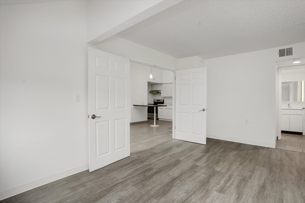 a living room and kitchen with white walls and wood flooring