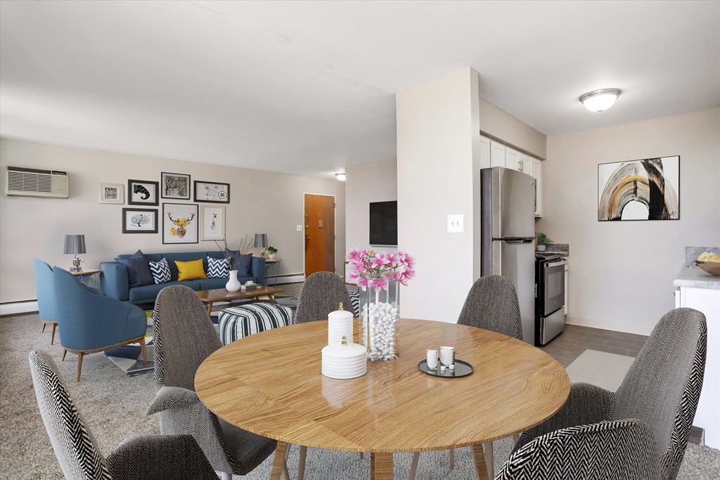 a dining area with a table and chairs and a living room in the background