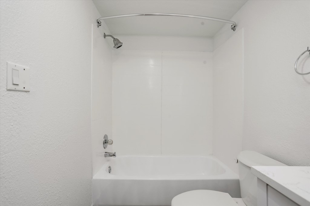 a white bathroom with a tub and a toilet