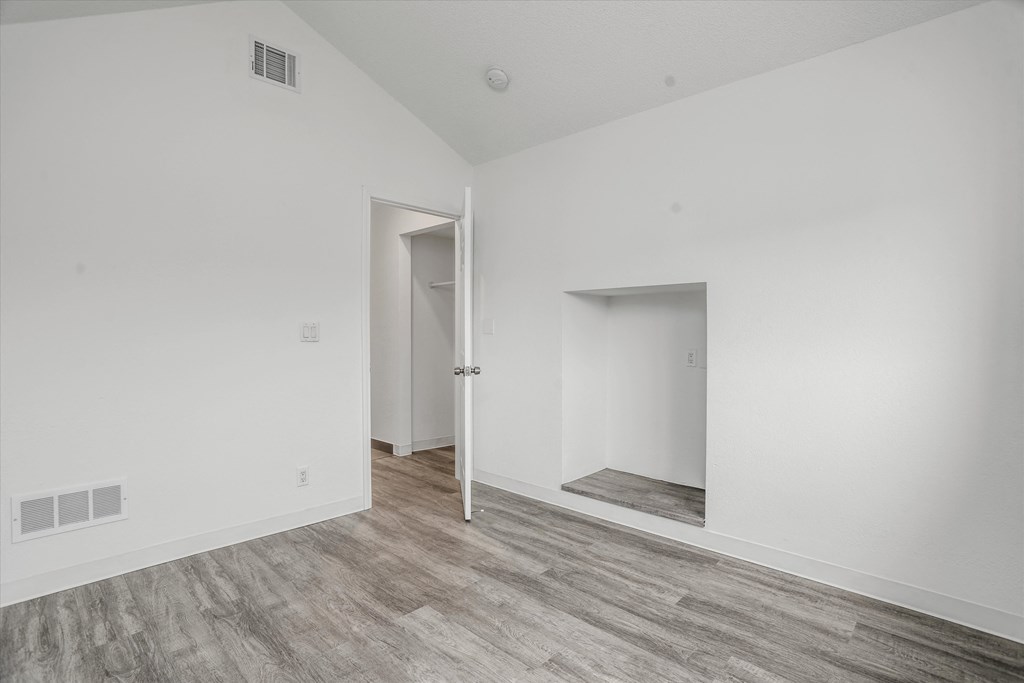 a bedroom with white walls and wood flooring and a closet