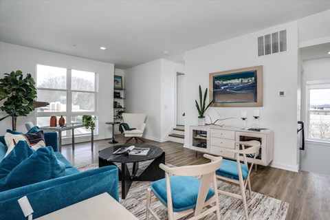 A living room with a blue couch and a painting on the wall.
