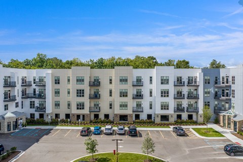 an aerial view of an apartment building with parking lot and cars