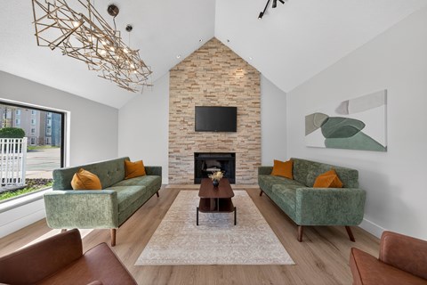 A living room with a fireplace and two green couches.