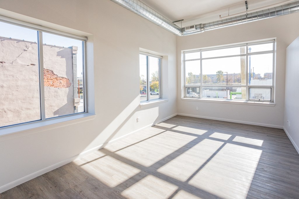 A sunny room with a large window and a wooden floor.