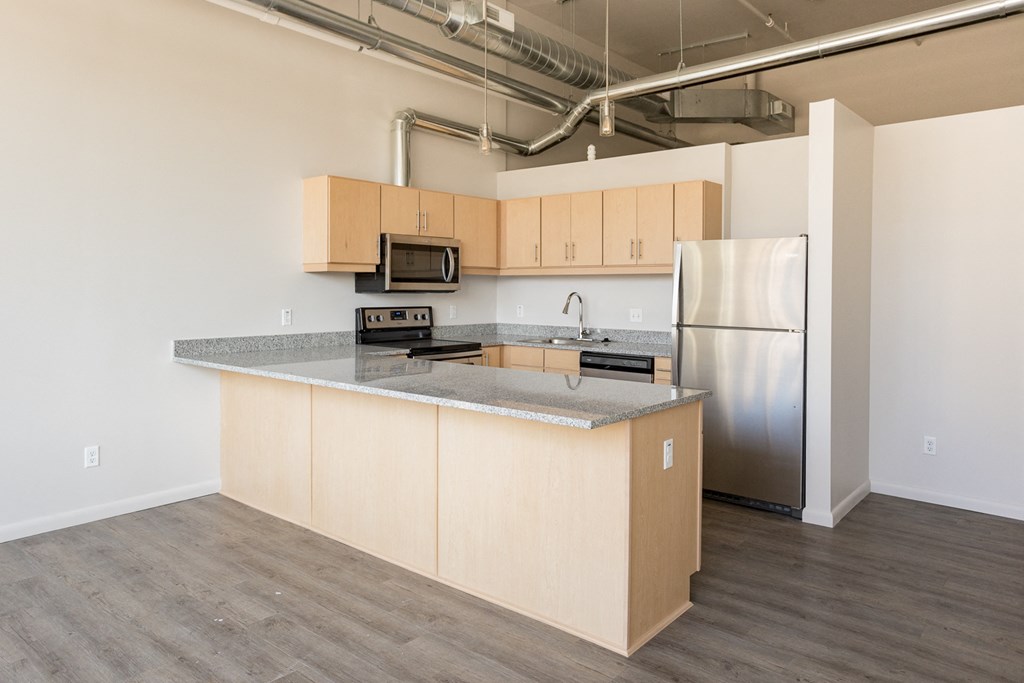 A kitchen with a refrigerator, microwave, and oven.
