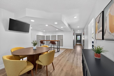 A modern dining room with a round table and yellow chairs.