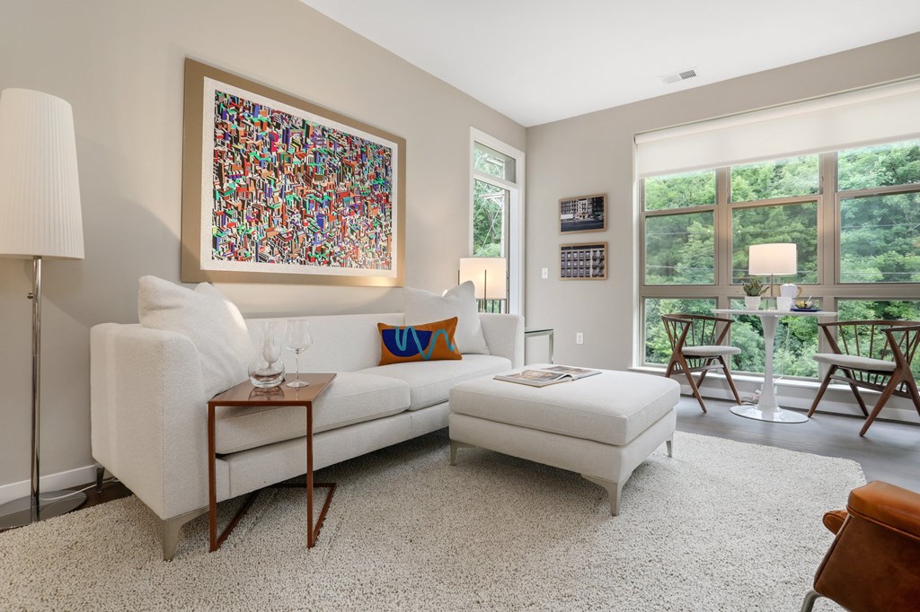 a living room with a white couch and a chair and a large window